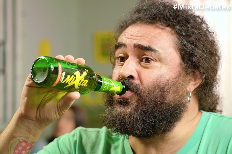 Imagen de El Sevilla de Mojinos Escozíos sosteniendo y bebiendo un botellín de Mixta en la campaña de Branded Content: El Debatex.