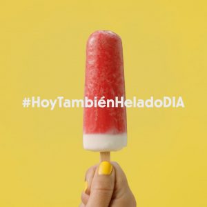 Imagen en primer plano de los vídeos publicitarios, de mano sosteniendo un helado rojo con texto promocional "#hoytambiénheladodia". Promoción de helados de Supermercados Dia. Confía en Colirio Films para tus videos publicitarios y contenido de marca.