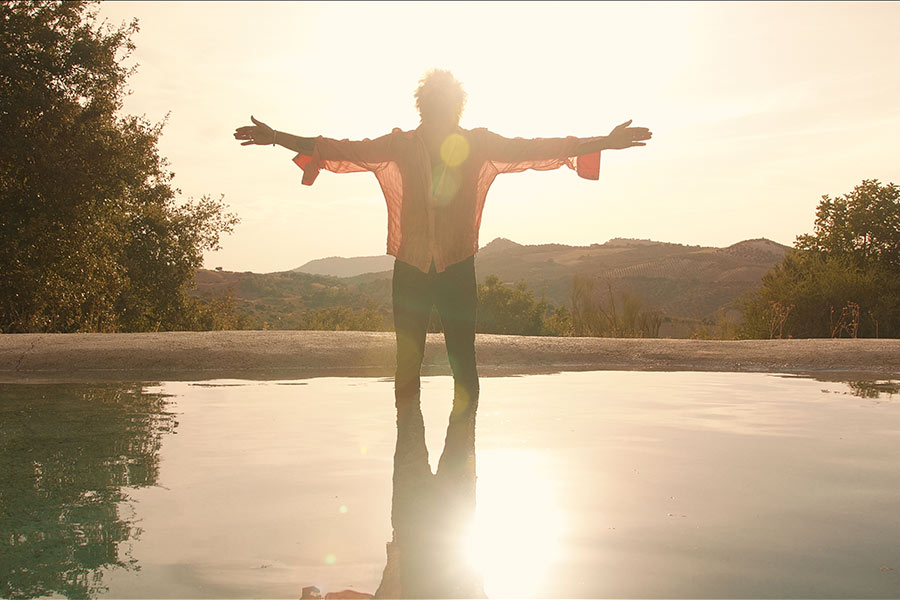 Atardecer dorado en la sierra de Cádiz, El Canijo de Jerez mirando al cielo con los brazos extendidos en un estanque, fotograma del videoclip No Tengas Miedo