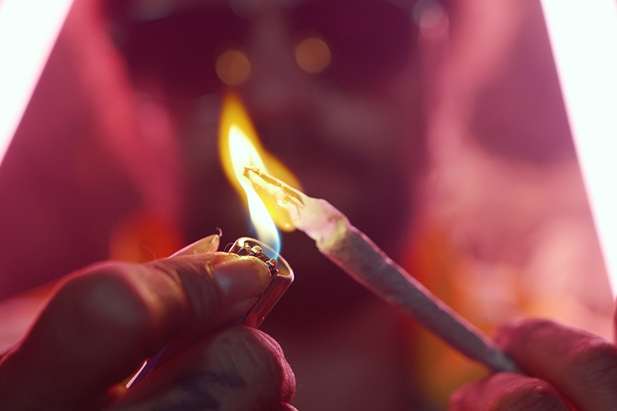 Primer plano de una mano encendiendo un porro durante el videoclip