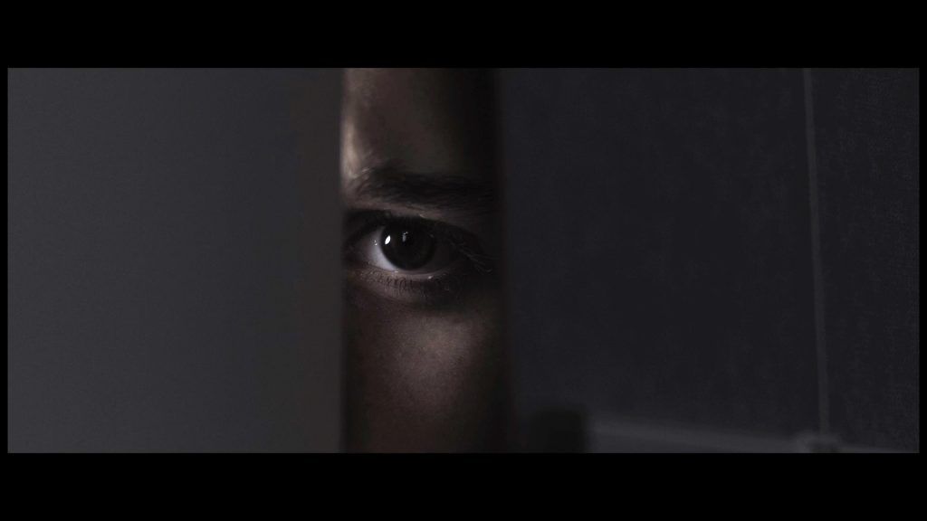Primer plano de un inquietante ojo asomándose por una rendija de la puerta - Ready or Not - Cortometraje de terror