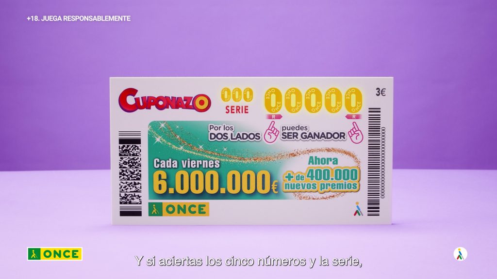 Fotografía de primer plano de un fondo morado y una mesa morada con un boleto de lotería ampliado del Cuponazo de La Once. El boleto de lotería se encuentra de pie, y los ceros en la parte superior están pintados en amarillo dorado. Productora audiovisual en Madrid, Colirio Films.